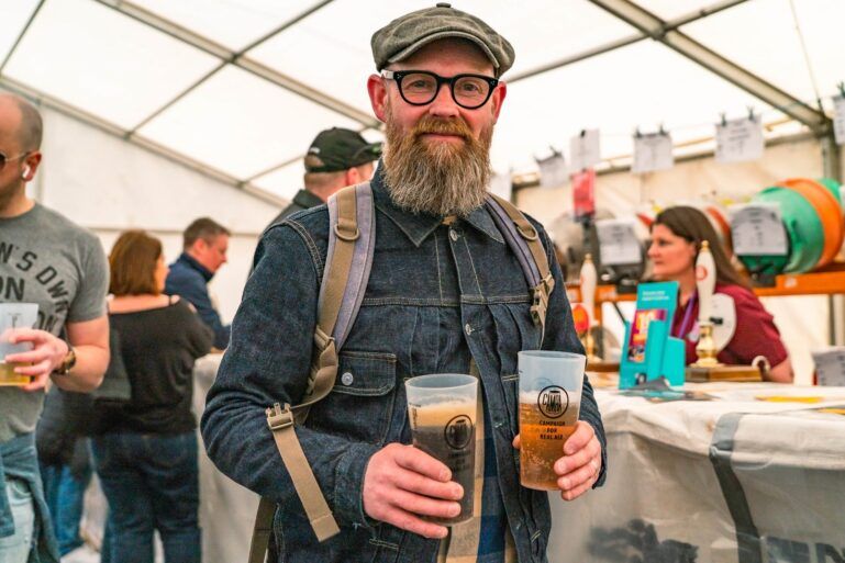 A person holing two pints of ale inside the beer tent at Paisley Food and Drink Festival 2023.