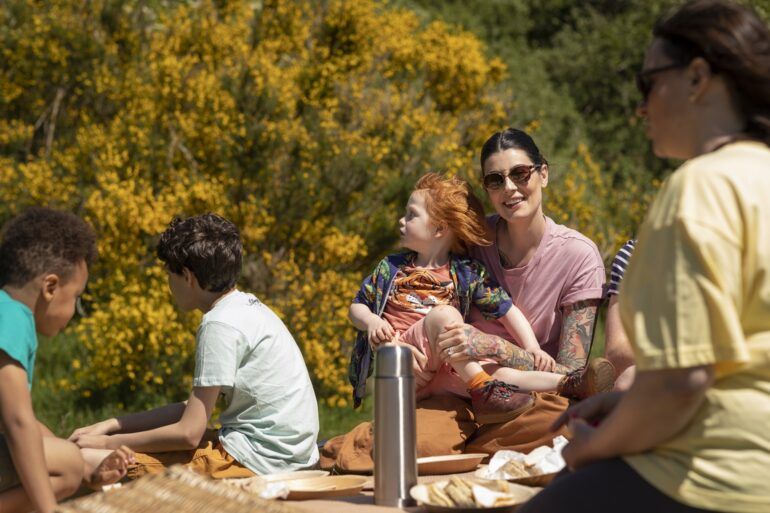 Woman looks to camera with child sitting on lap at family picnic