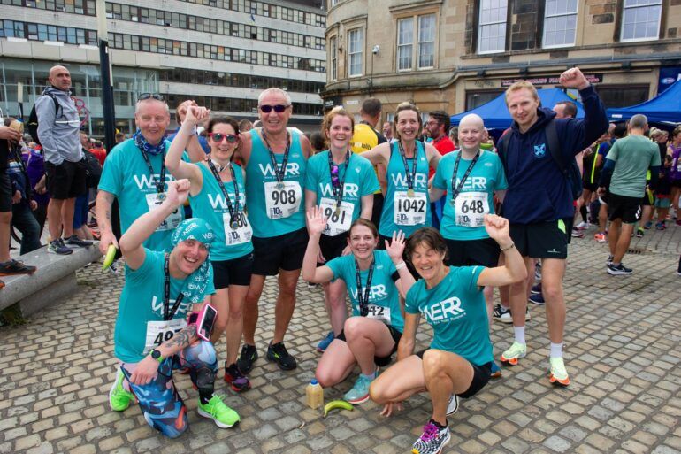 Group of runners pose for camera at finish of Paisley 10k Road Race 2022