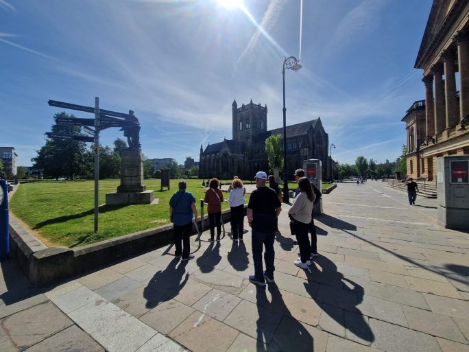 A Paisley Tours tour group outside Paisley Abbey and Paisley Town Hall on a sunny day.